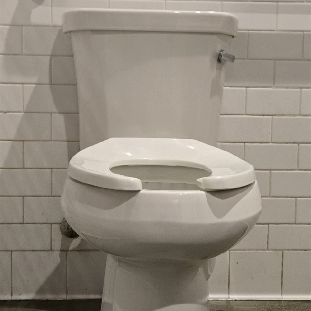 A new commercial toilet installed in a subway tile restroom