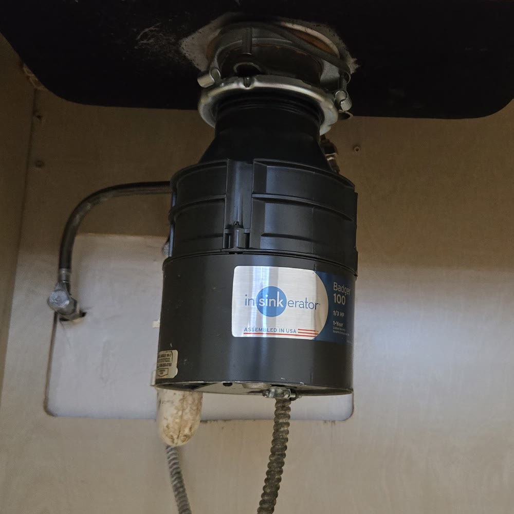 Garbage disposal under a dark composite sink.