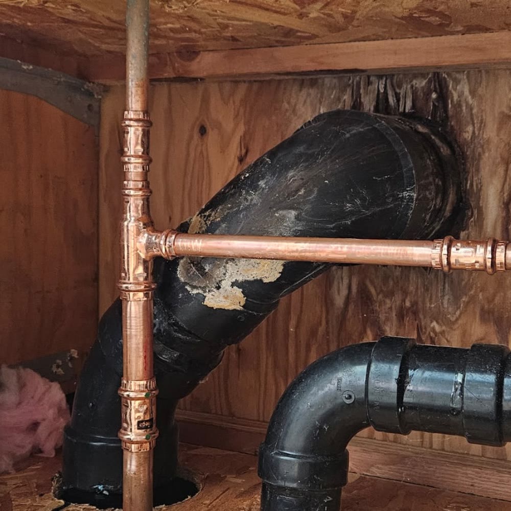 New copper tee with press fittings beside a drain line.