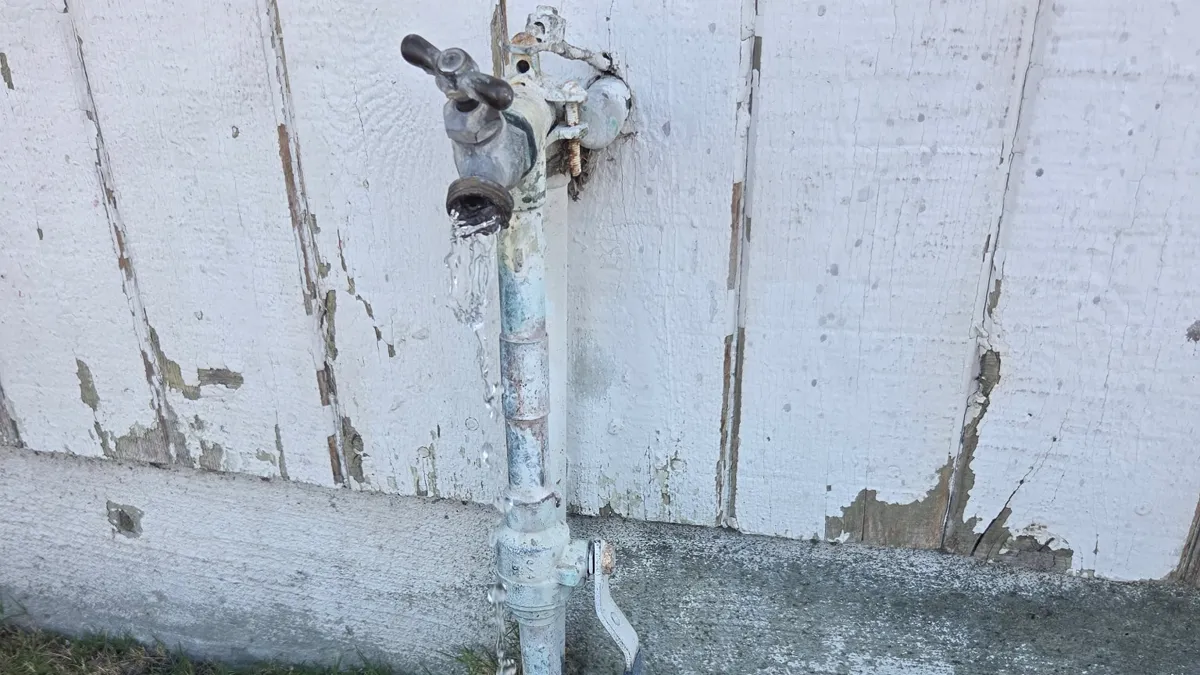A dripping outdoor spigot on an exterior wall before a smart water shutoff was installed.