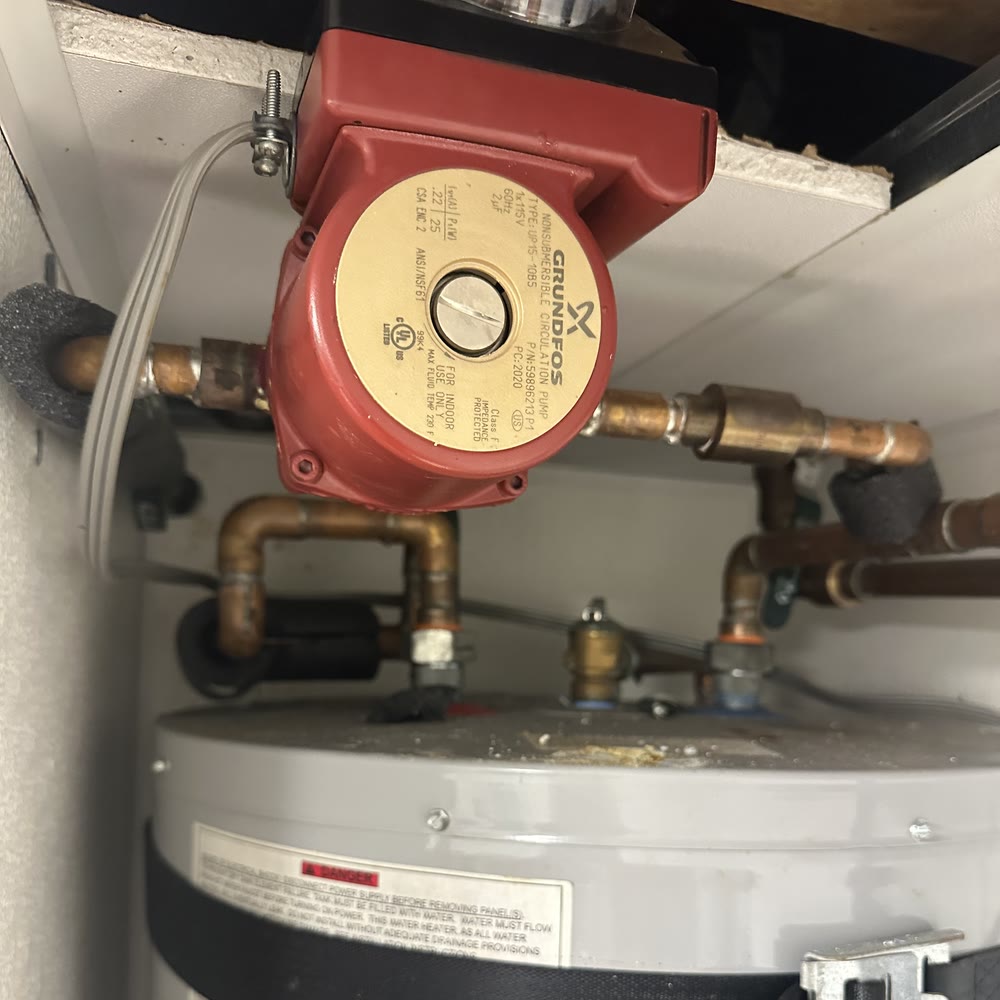Hot water recirculation pump on copper beside a water heater.
