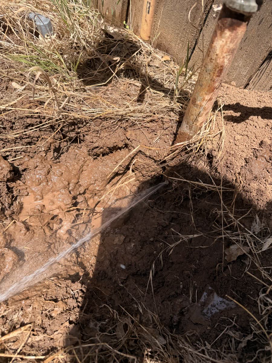 Water spraying from a leak at the base of a corroded riser pipe.