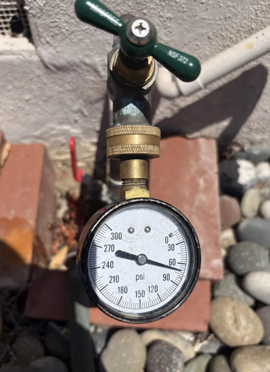 A water pressure test gauge on a residential hose bib reading past 270 psi.